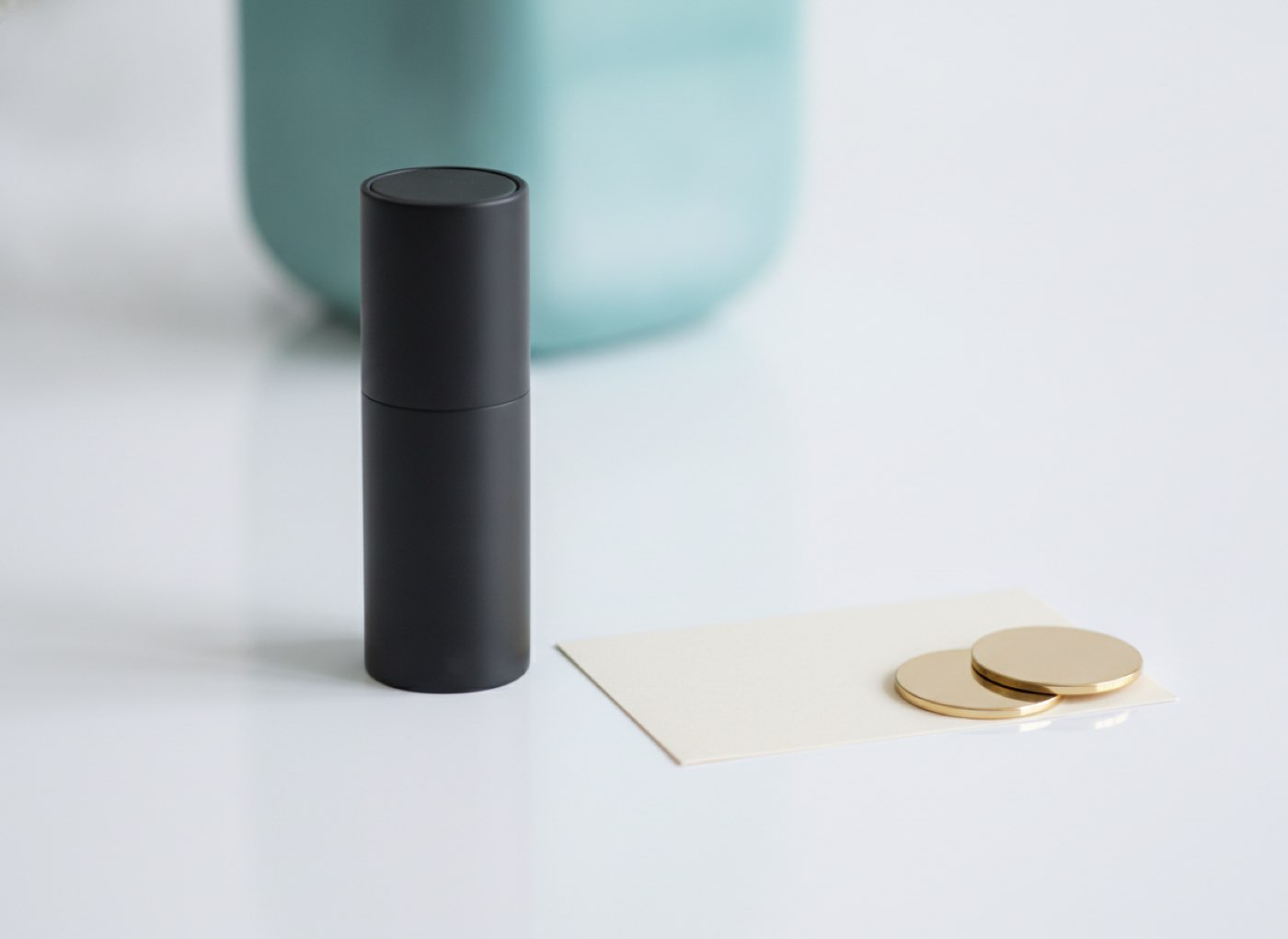 A hardware wallet device, a blank card and two coins on a white desk